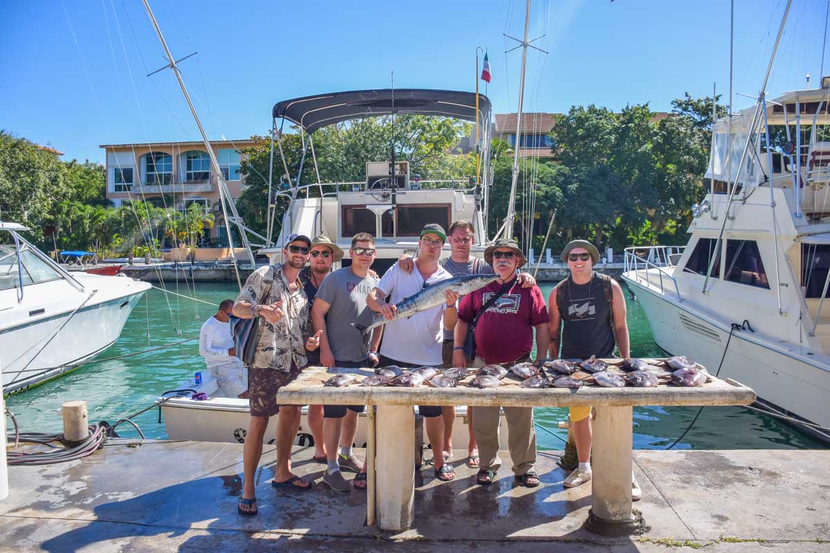 Daniel and his friends stand in front of their catch from their fishing tour in Puerto Vallarta at the end of the tour