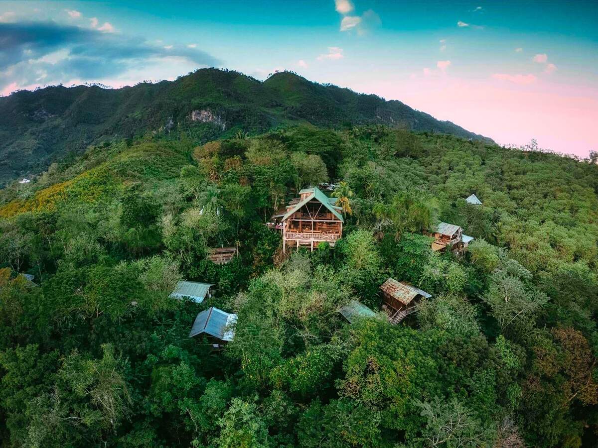 Utopia Eco Hotel sits on a tree covered hillside in an aerial view