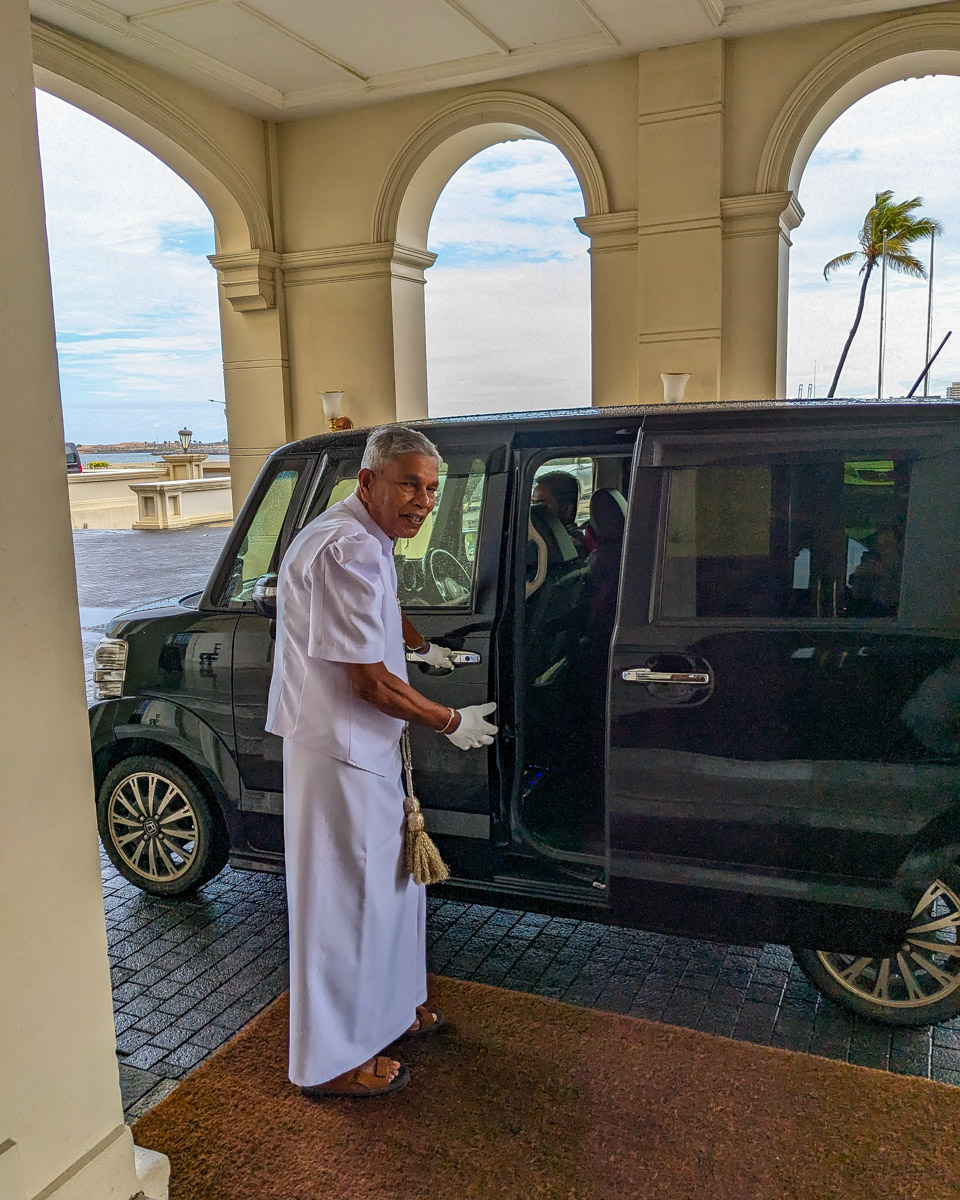 A Sri Lankan concierge invites us into our tour vehicle at the Galle Face Hotel in Colombo, Sri Lanka