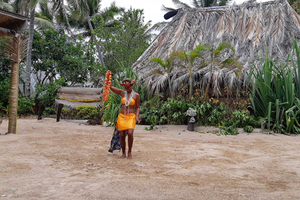A fijian woman holding flowers and dancing as part of a performance robinson crusoe island fiji