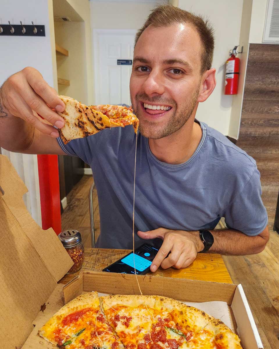 Daniel enjoys a slice of pizza on a food tour in Georgetown Washington DC