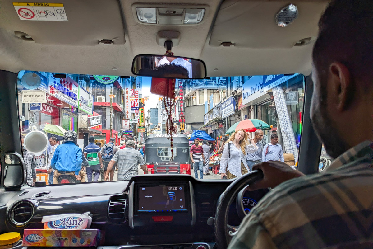 Looking out the front of our tour vehicle as our guide drives us through a crowded market selling different items Colombo, Sri Lanka