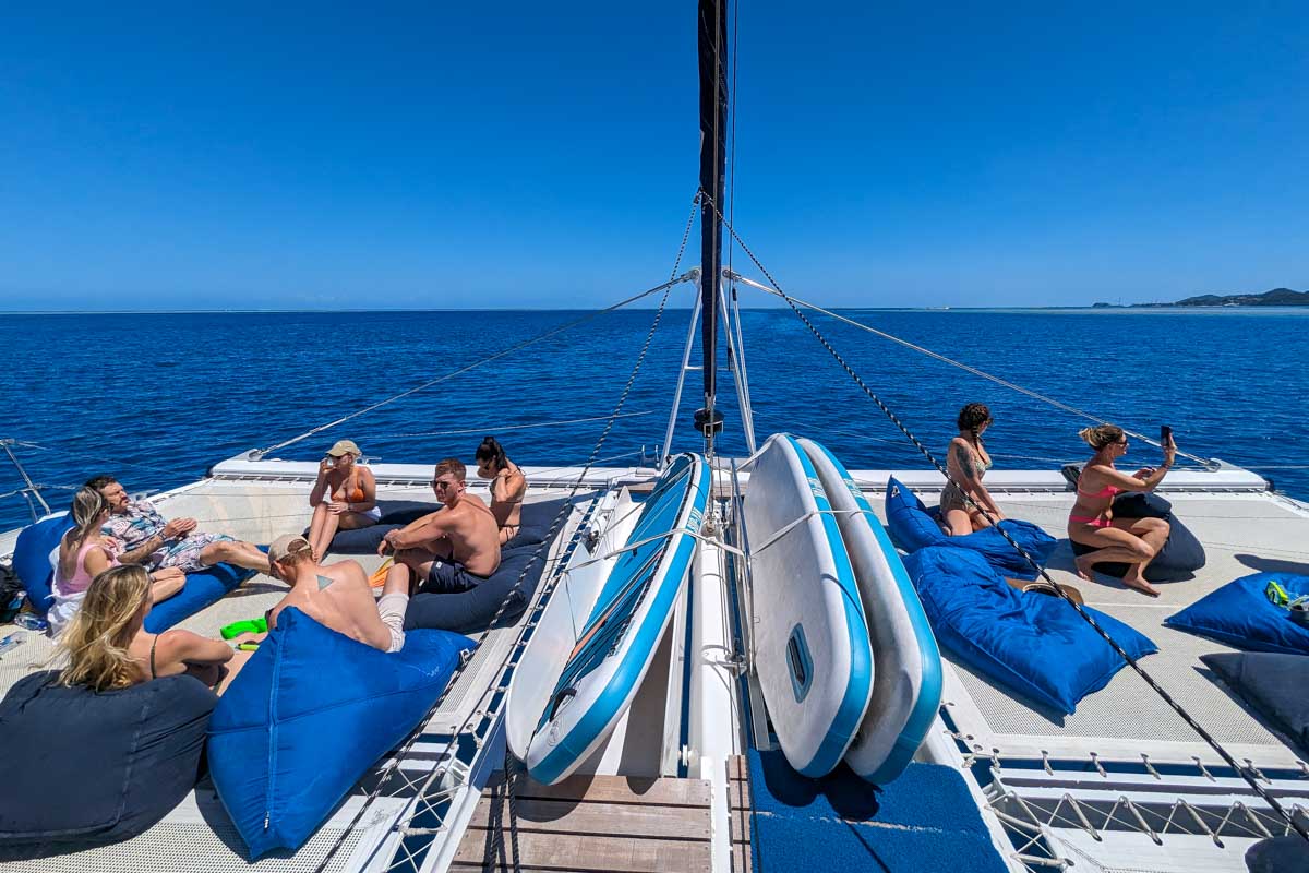 Stand up paddle boards on the deck of the sabre catamaran with other people talking and taking photos Fiji