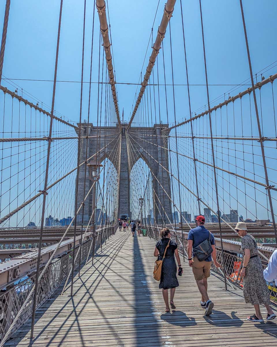 The Brooklyn Bridge tower as people walk below in NYC