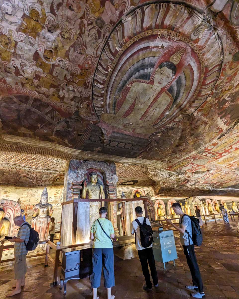 Tourists admire paintings on the ceiling of Dambulla Cave Temple Sri Lanka