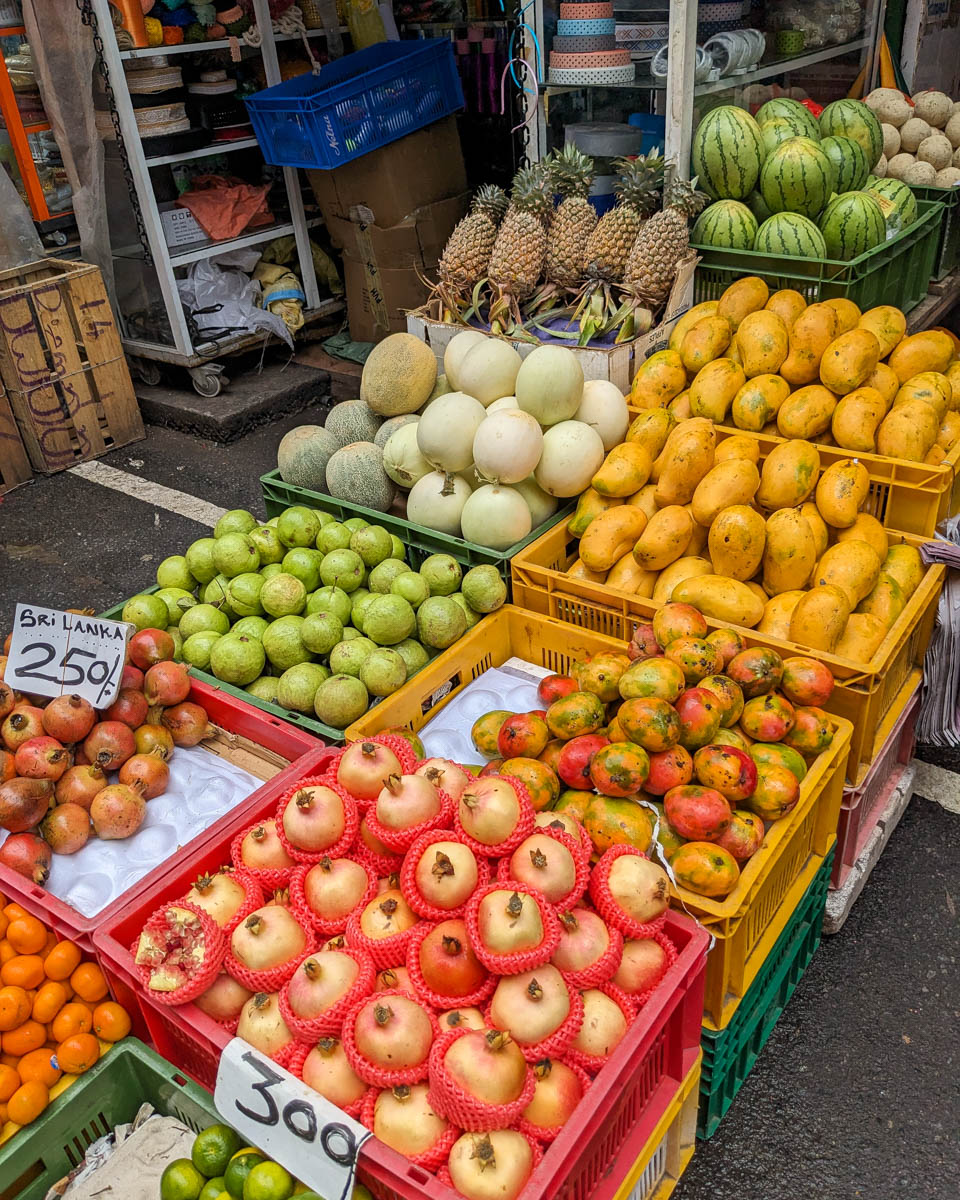 Various fruits such as apples, pomegranate, and mango on display at a street vendor stand in Colombo, Sri Lanka