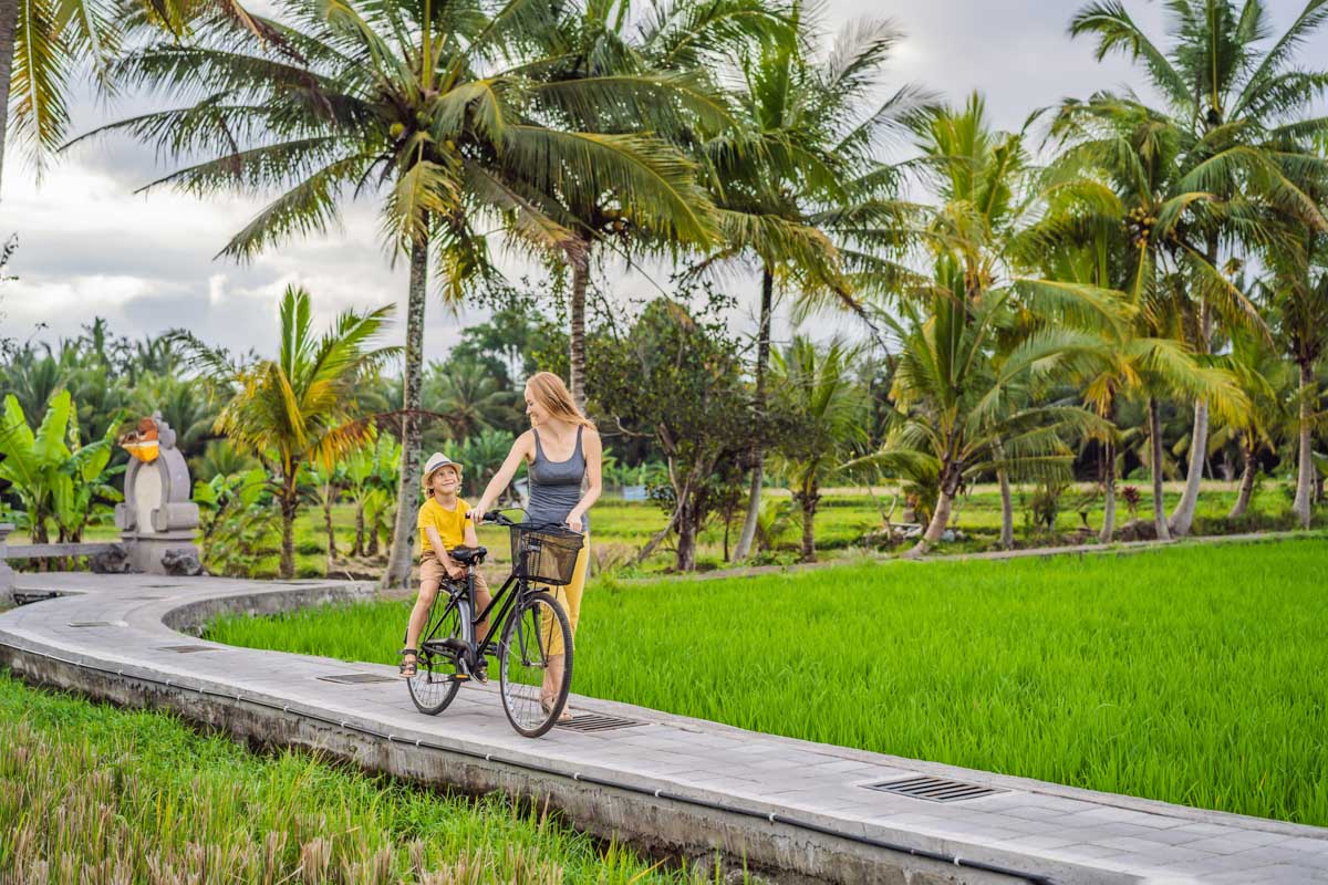 A lady and her child ride a bike through Ubud on a bike tour