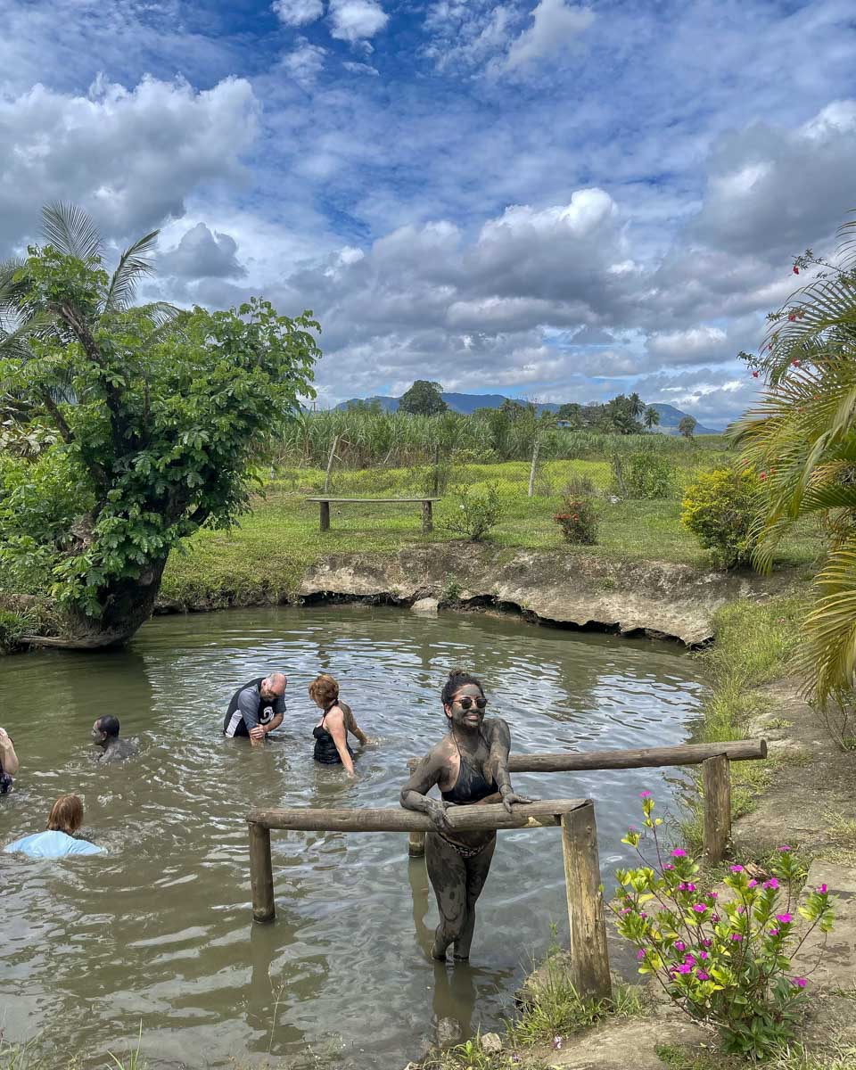 A woman smiles coming out of a hot spring at sabeto mud pool hot springs fiji