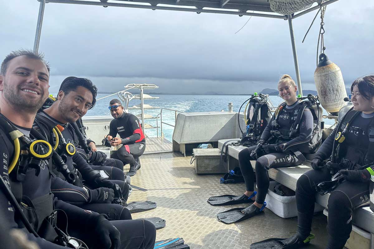 Daniel and Bailey and friends smile on a boat on the ocean during a shark dive fiji