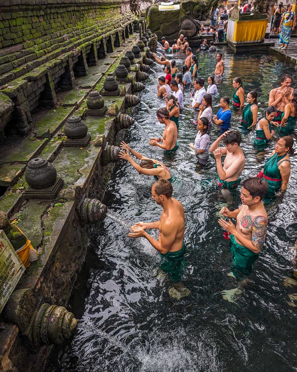 Daniel splashes himself with water at Pura Tirta Empul Temple in Ubud, Bali