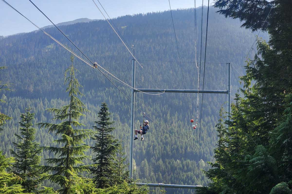 Man coming down zipline as seen from the bottom whistler, canada, sasquatch zipline
