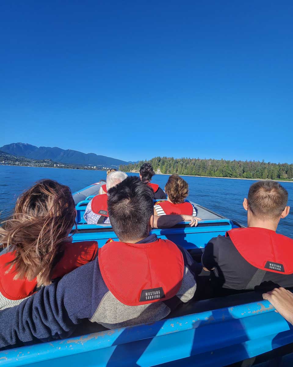 Sightseers enjoy boating past stanly island on the zodiac in Vancouver, Canada