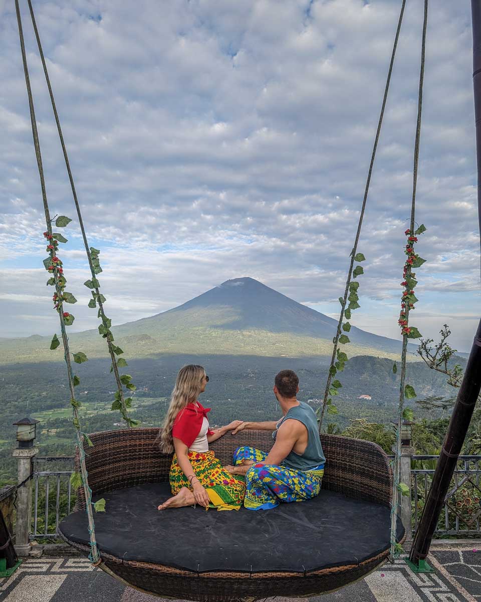Bailey and Daniel sit on a swing at Lempuyang temple during the Bali instagram tour