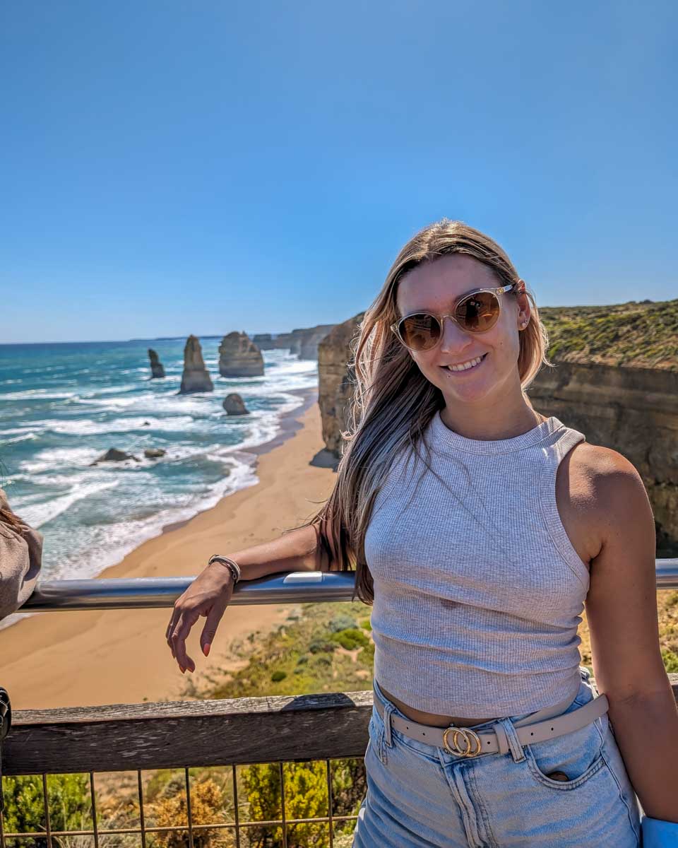 Bailey smiles and poses by twelve apostles on a great ocean road tour australia