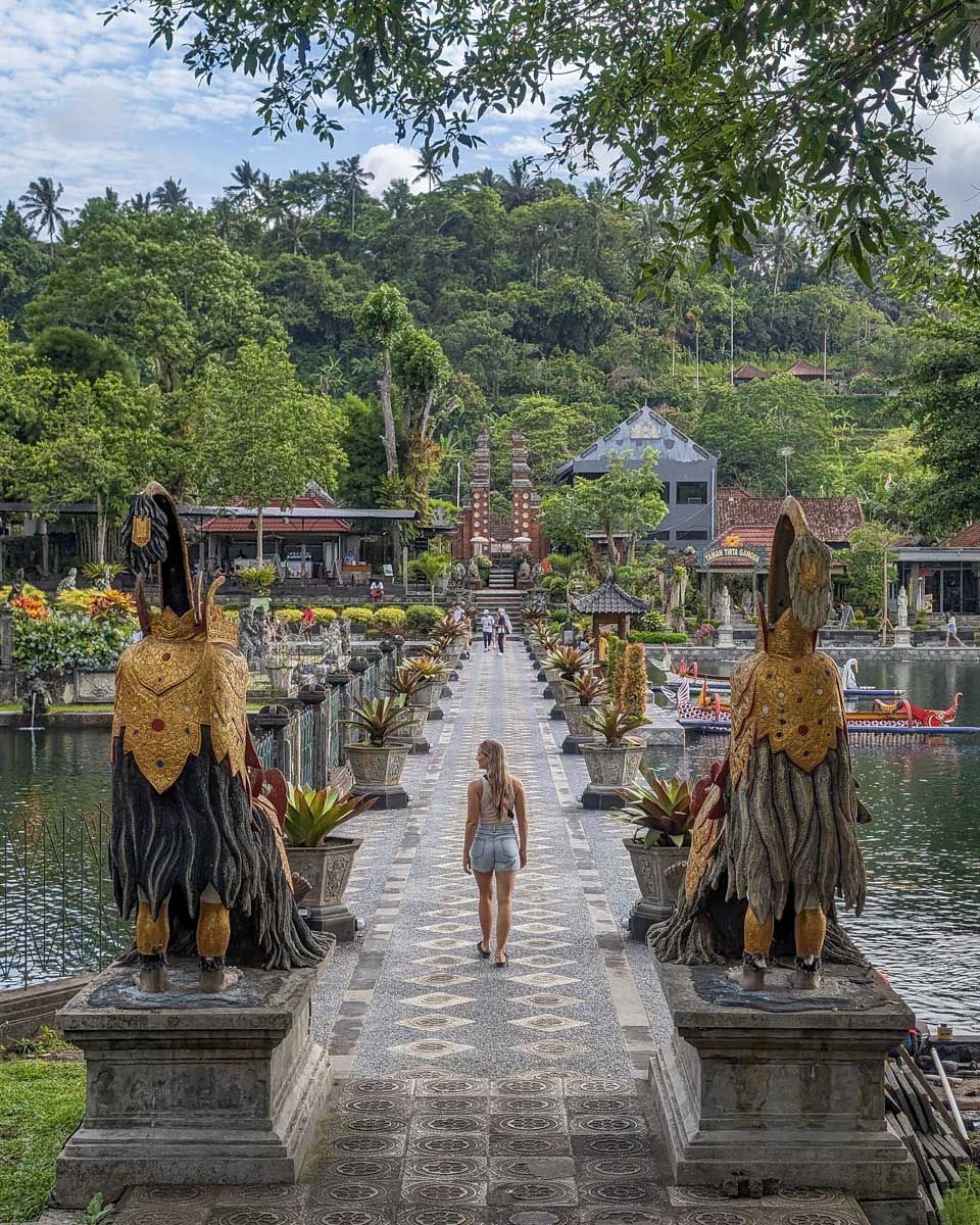 Bailey walks across a bridge at tirta gangga on the instagram tour bali