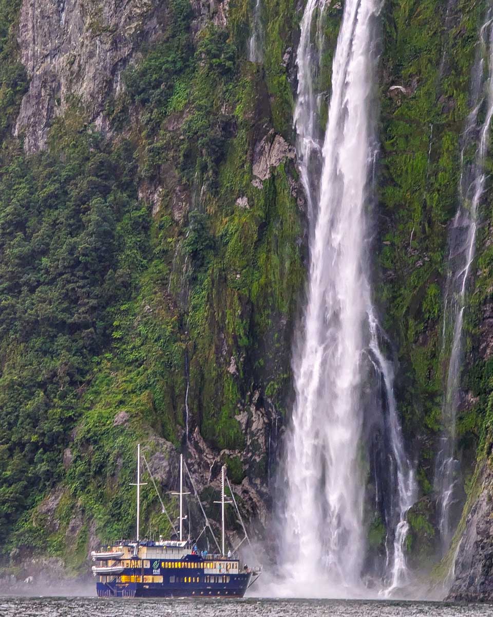 A boat gets close to Bowen Falls on a milford sound cruise new zealand