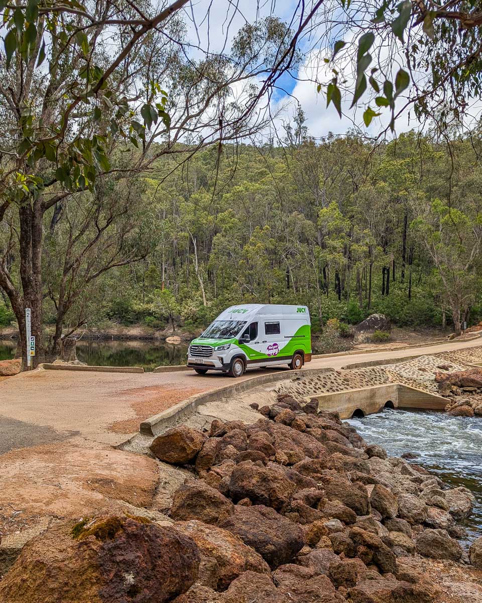 A JUCY campervan driving in Australia by a river