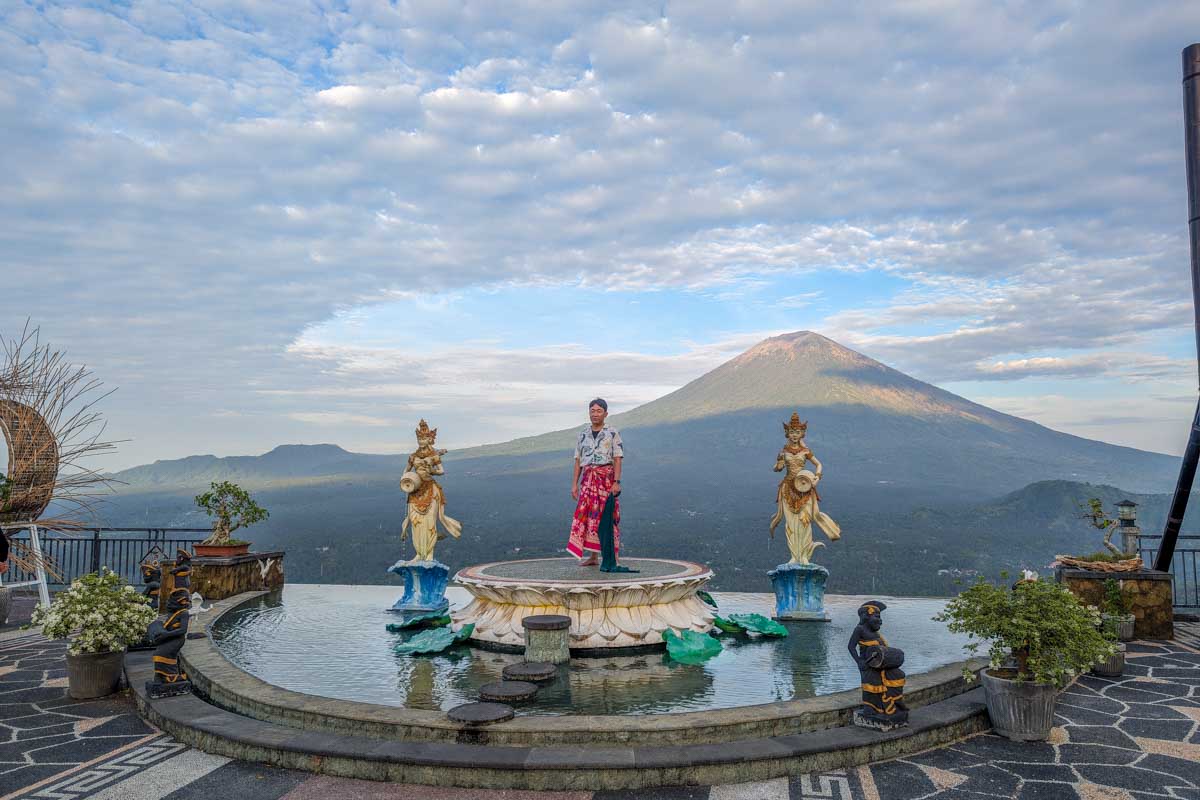 A man stands for a photo at Lempuyang temple with Mount Agung in the background Bali