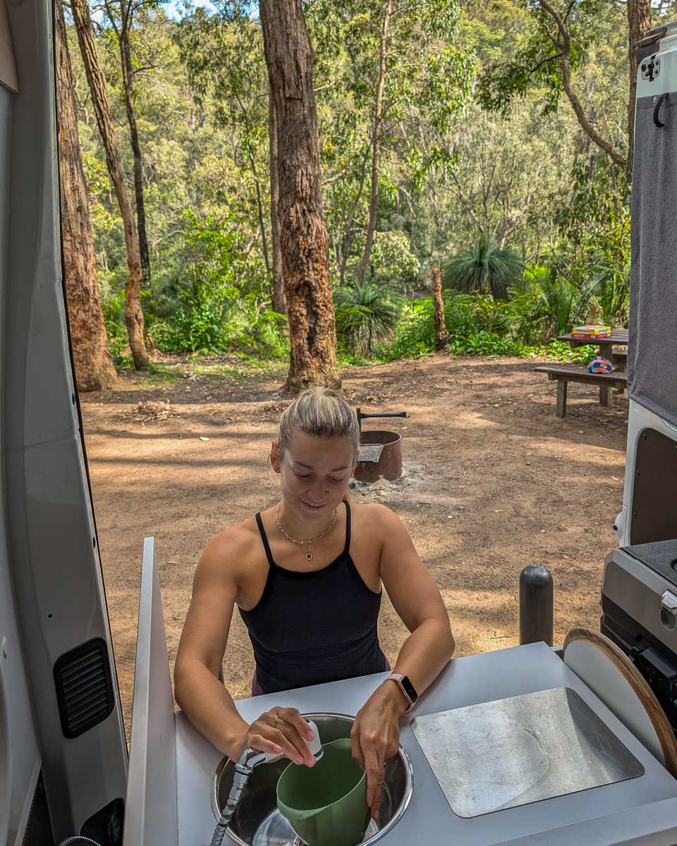 Bailey washing dishes at the back of a JUCY campervan in Australia