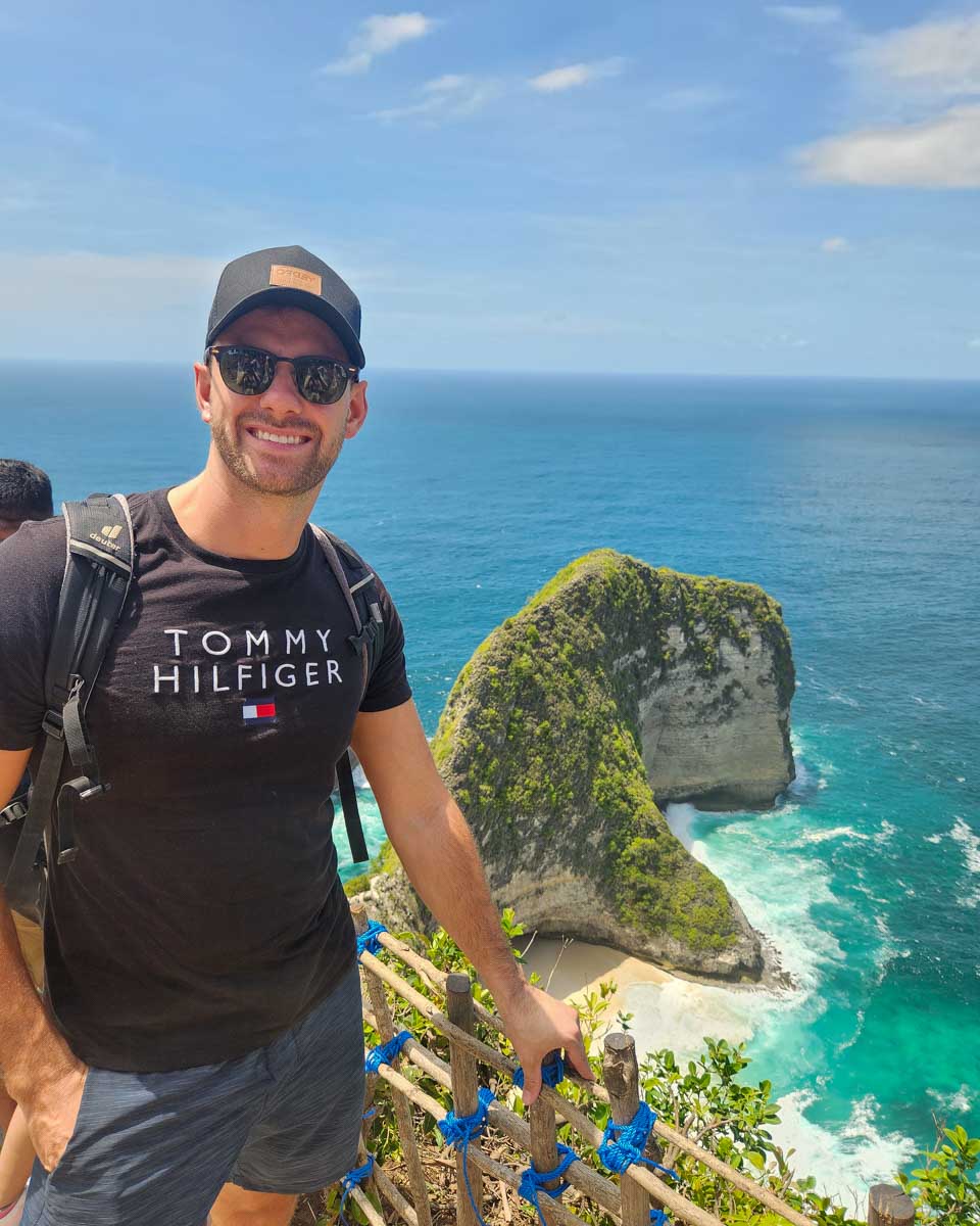 Daniel on stairs looking down at Kelingking Beach on a Nusa Penida tour in Bali