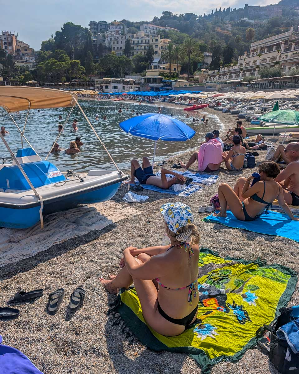 Bailey sitting on Mazzaro beach in Taormina Italy
