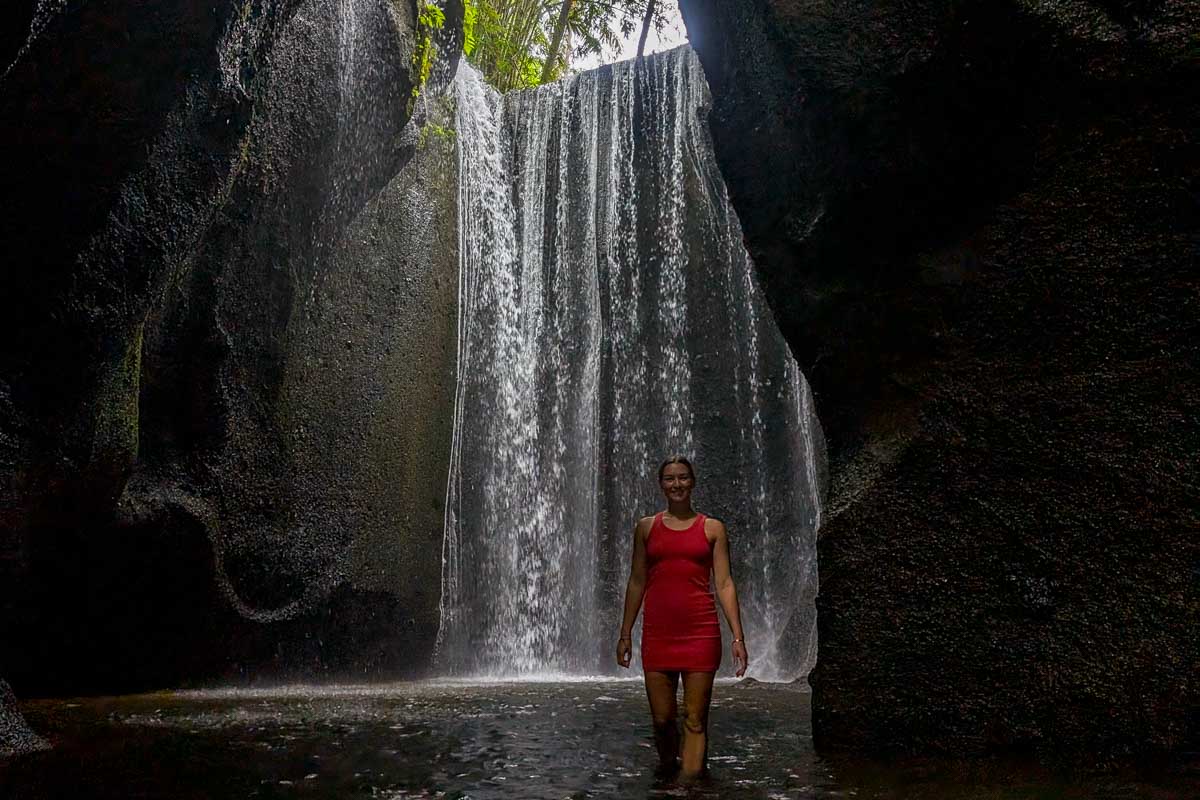 Bailey stands at Tukad Cepung waterfall in Bali on a waterfall tour