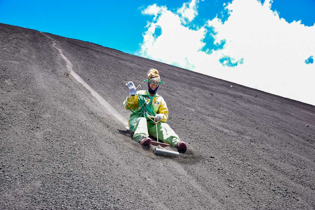 Bailey waves while volcano boarding down cerro negro in Nicaragua