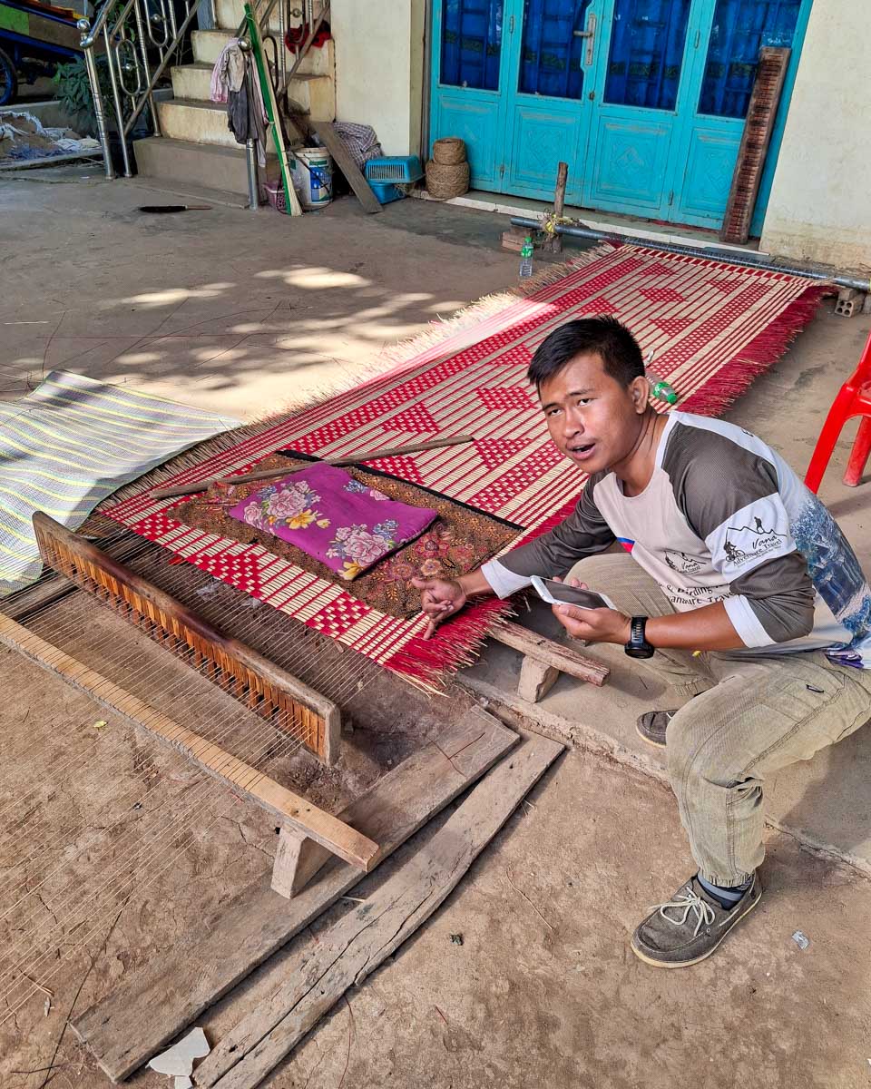 A Cambodian guide explains how trditional sleeping mats are made on a tour from Phnom Penh Cambodia