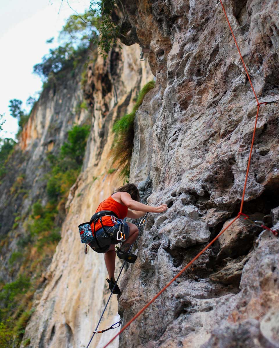 A person climbs a rock face near Krabi Thailand