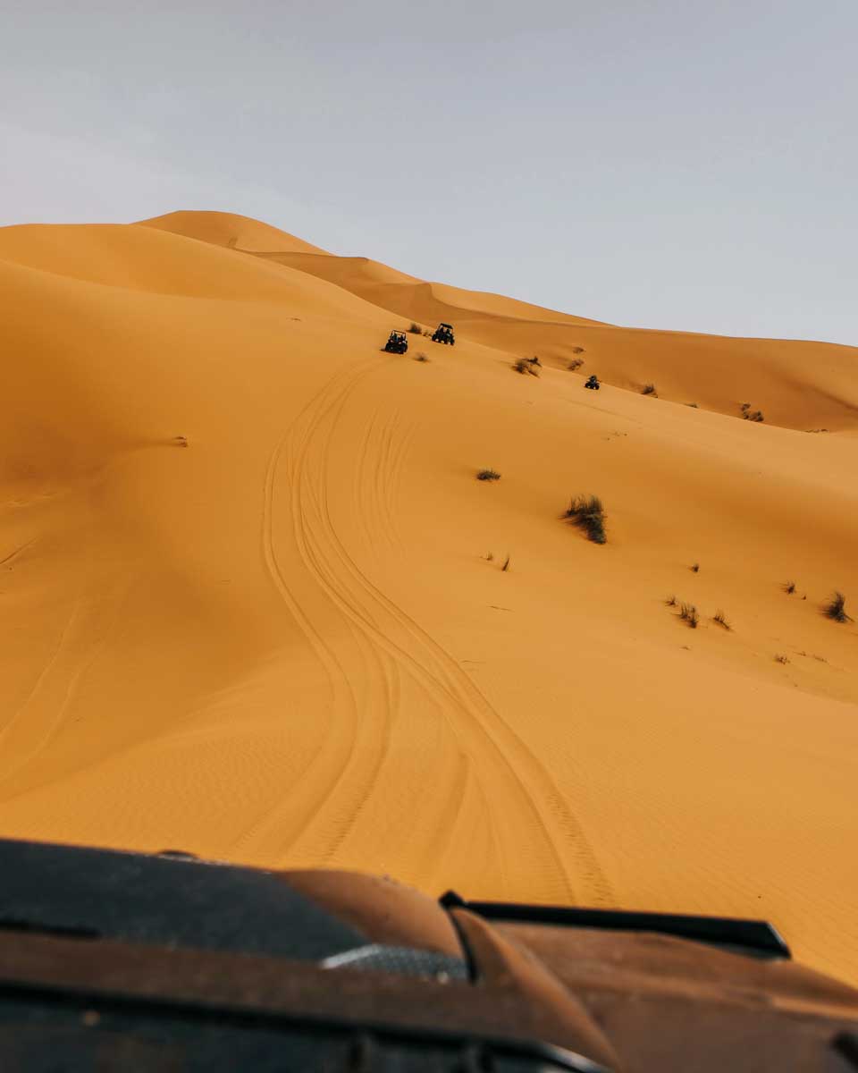 An SUV drives through the desert on a tour from Abu Dhabi