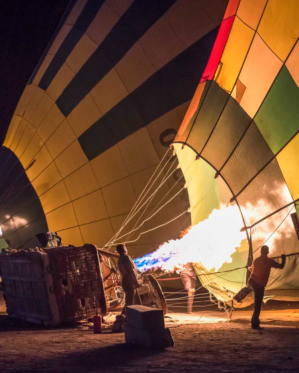People blow up a hot air balloon in the morning on a tour from Luxor Egypt