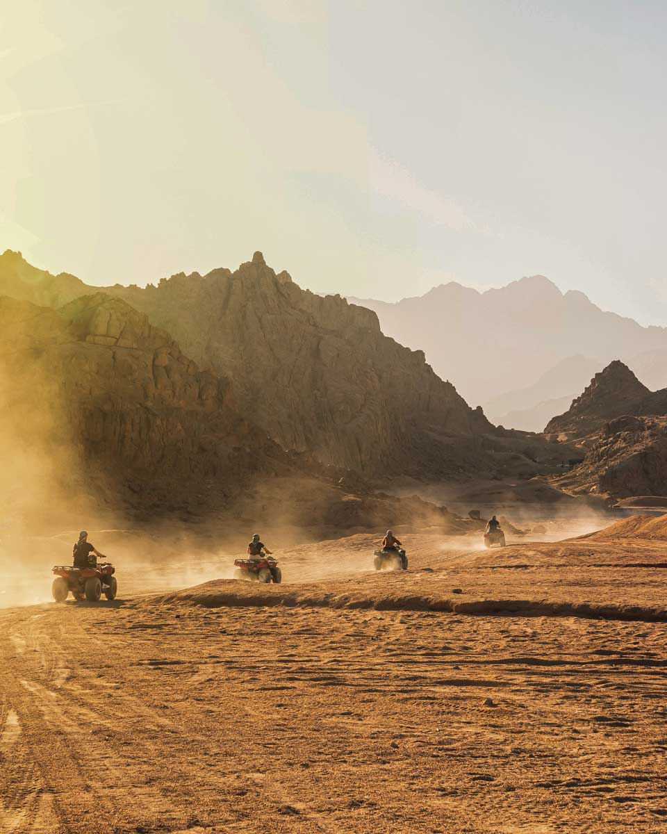 People ride through the desert at sunset on atvs on a tour from Luxor Egypt