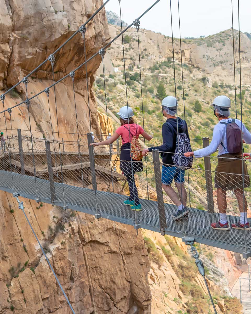 A group of people walk across a bridge on the Caminito del Rey trail in Spain
