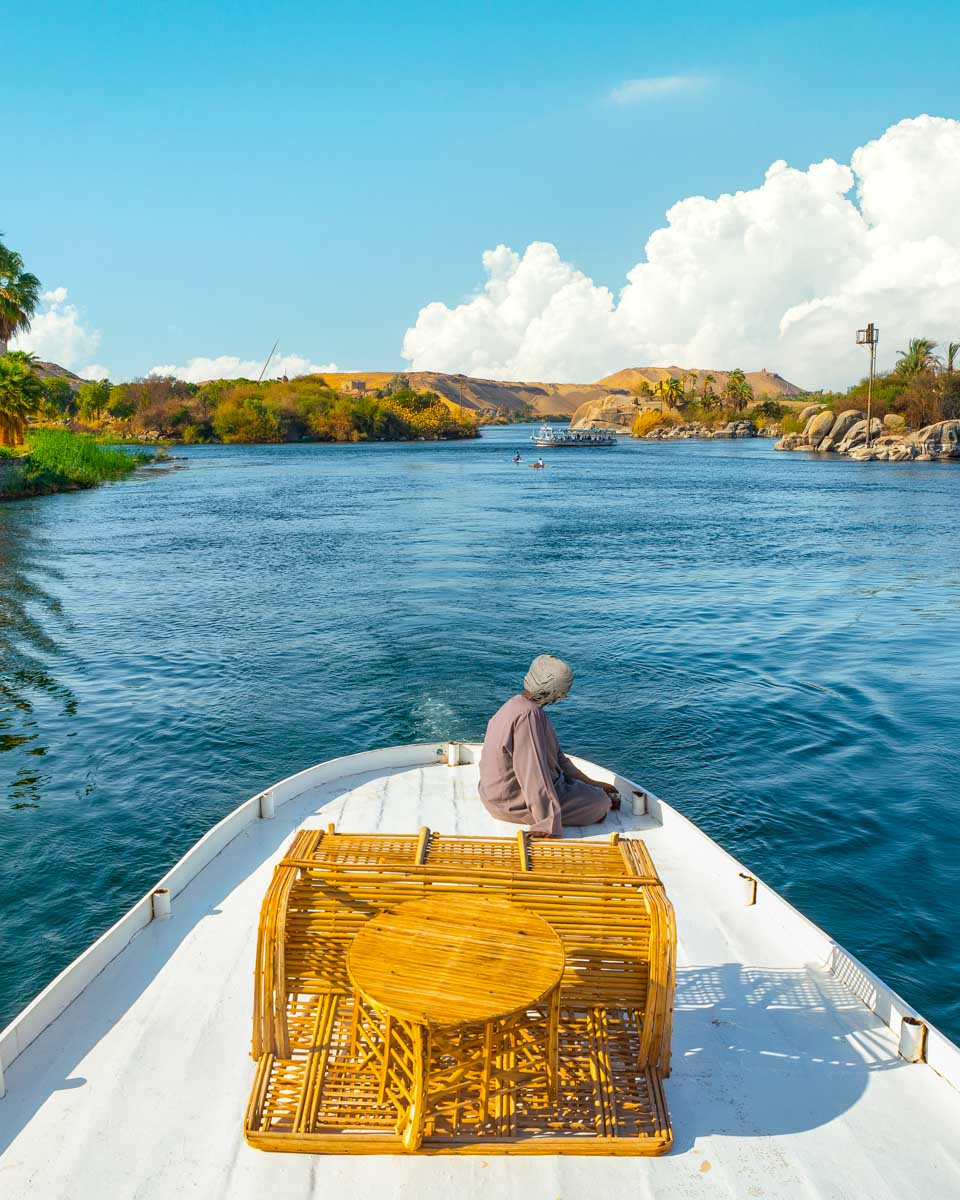 A man sitting on a felucca boat cruising down the nile from Aswan Egypt