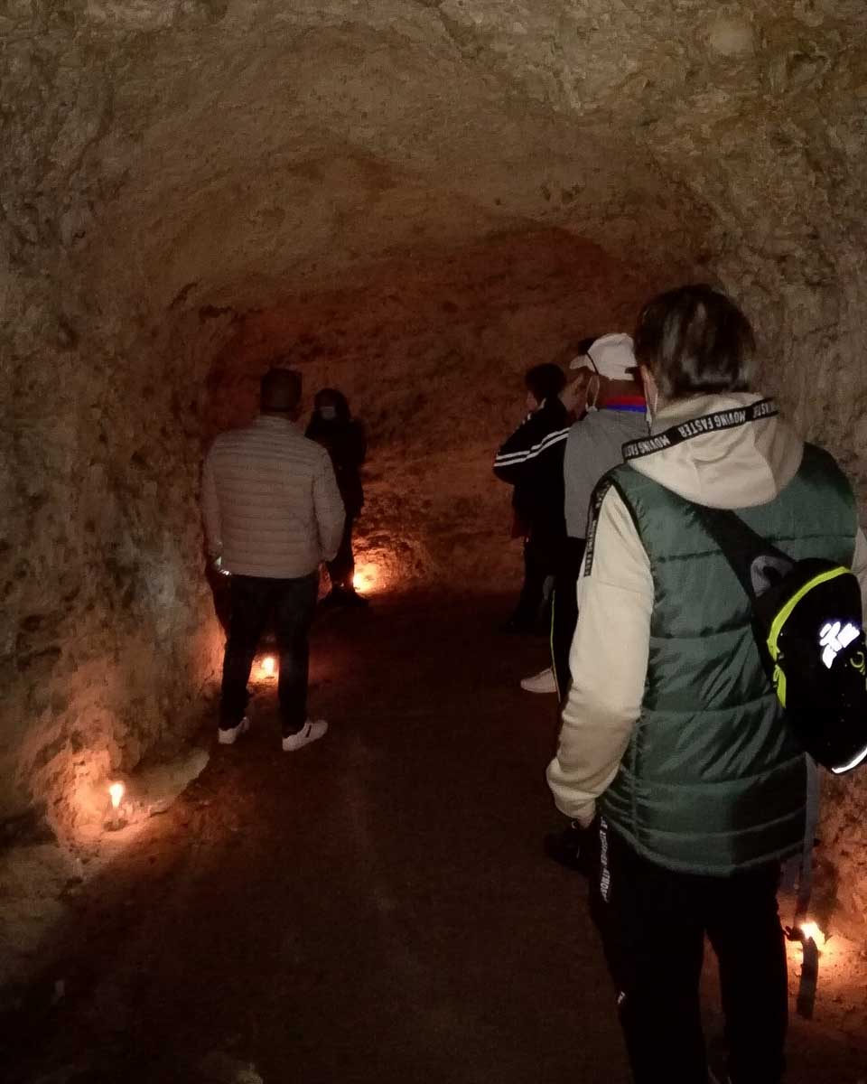 People in a candle lit underground tunnel on a tour in Cagliari Italy