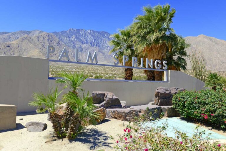 A sign saying Palm Springs with a desert background in Palm Springs California