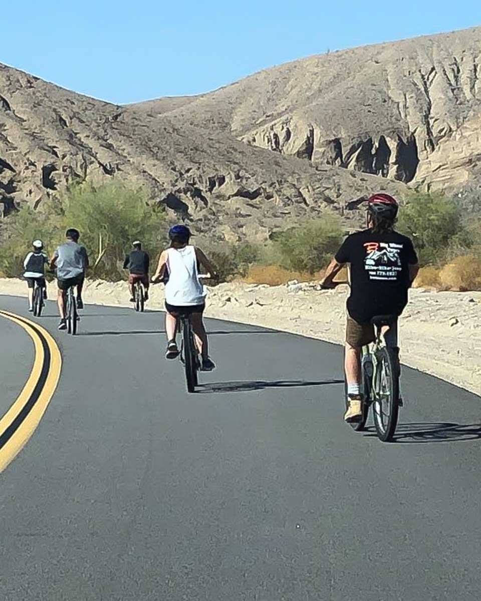 People cycle along the road in the desert on a tour from Palm Springs