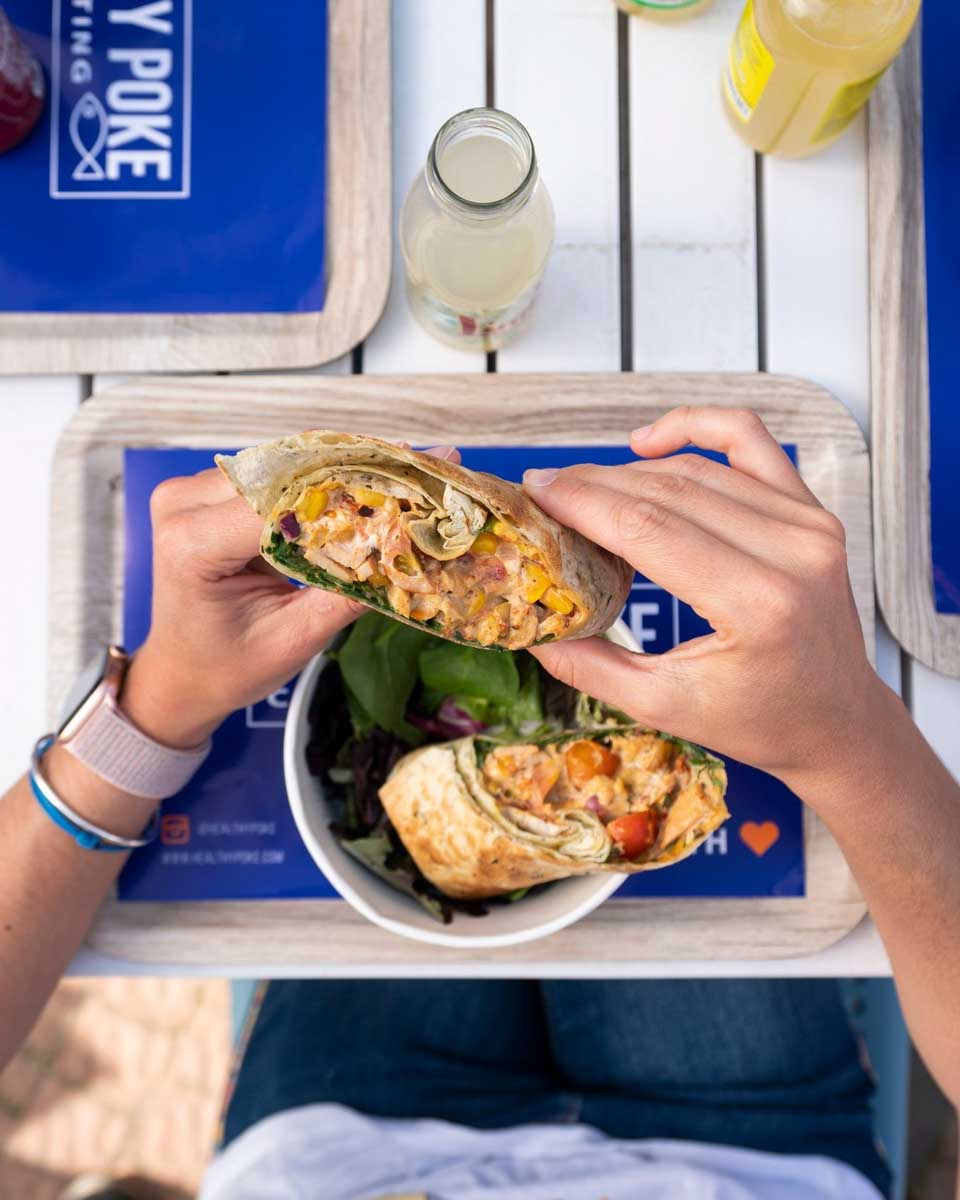 A person eats a wrap at Healthy Poke Seville