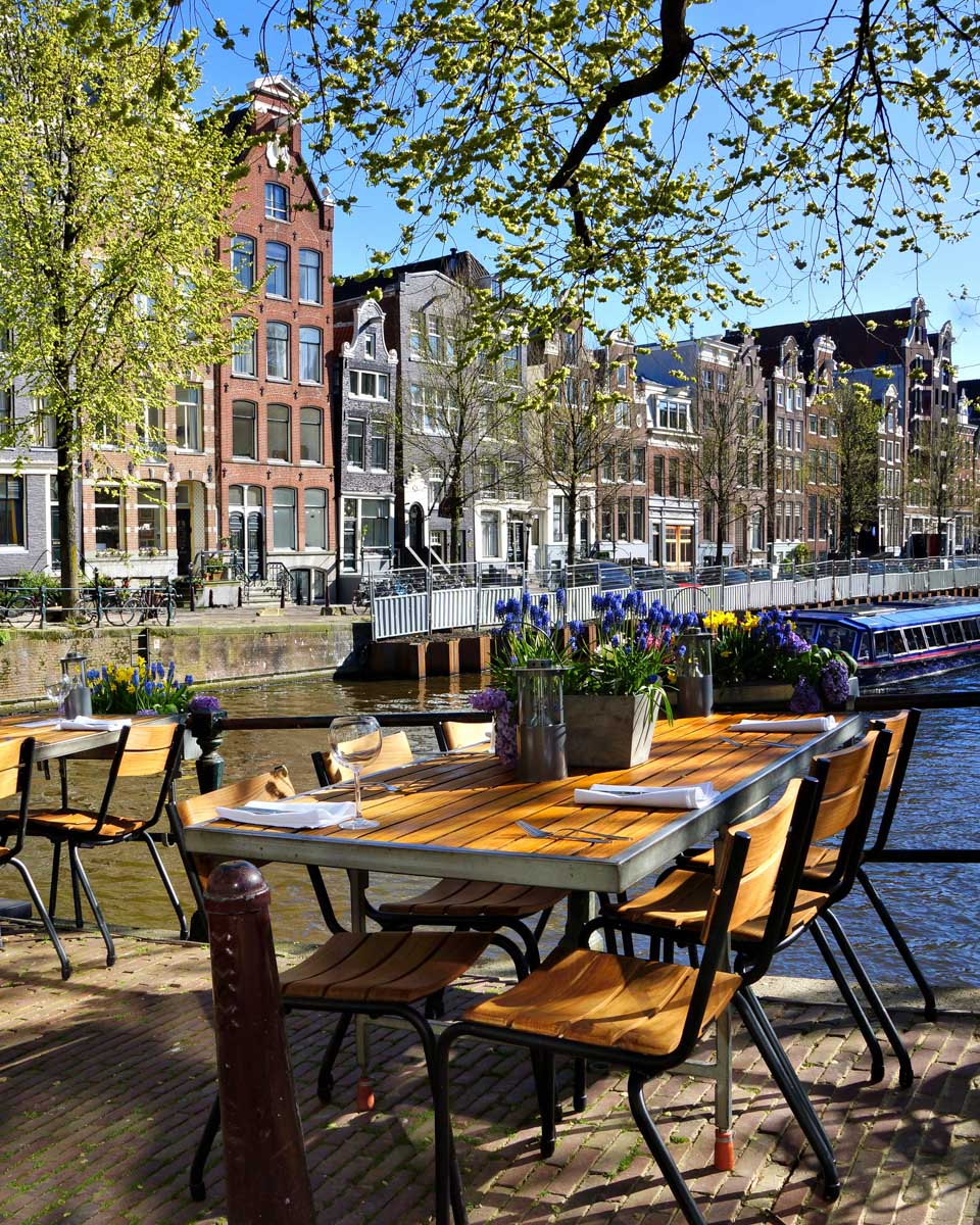 Restaurant tables lining the beautiful canals of Amsterdam