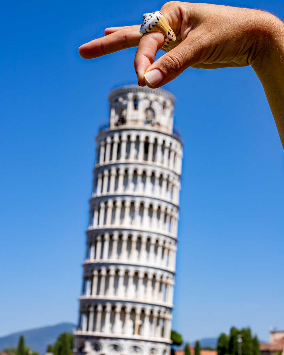 A person pretends to hold up the Leaning Tower of Pisa on a tour of Tuscany from Florence Italy