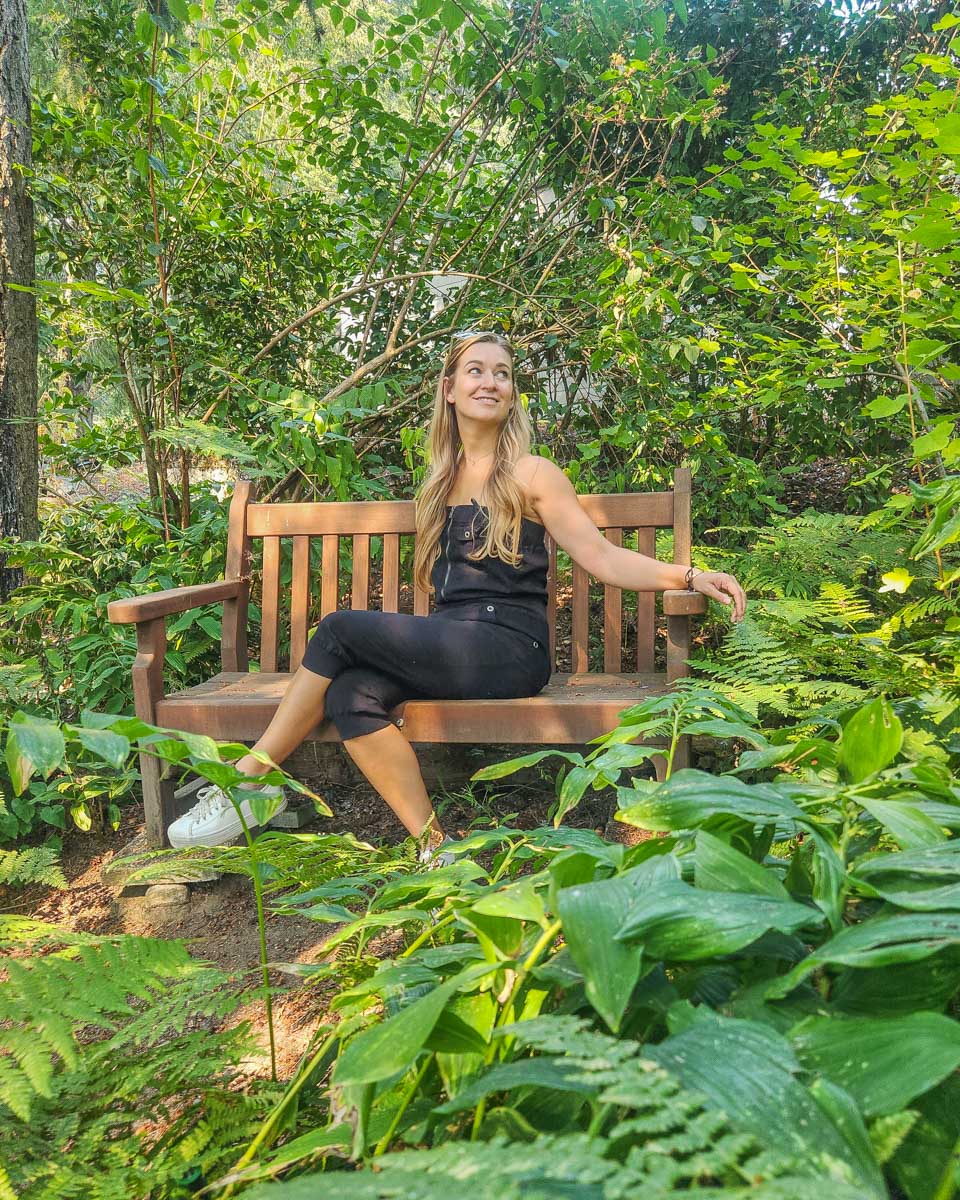 Bailey-sits-on-a-bench-surrounded-by-greenery-at-the-botanical garden in Anchorage Alaska