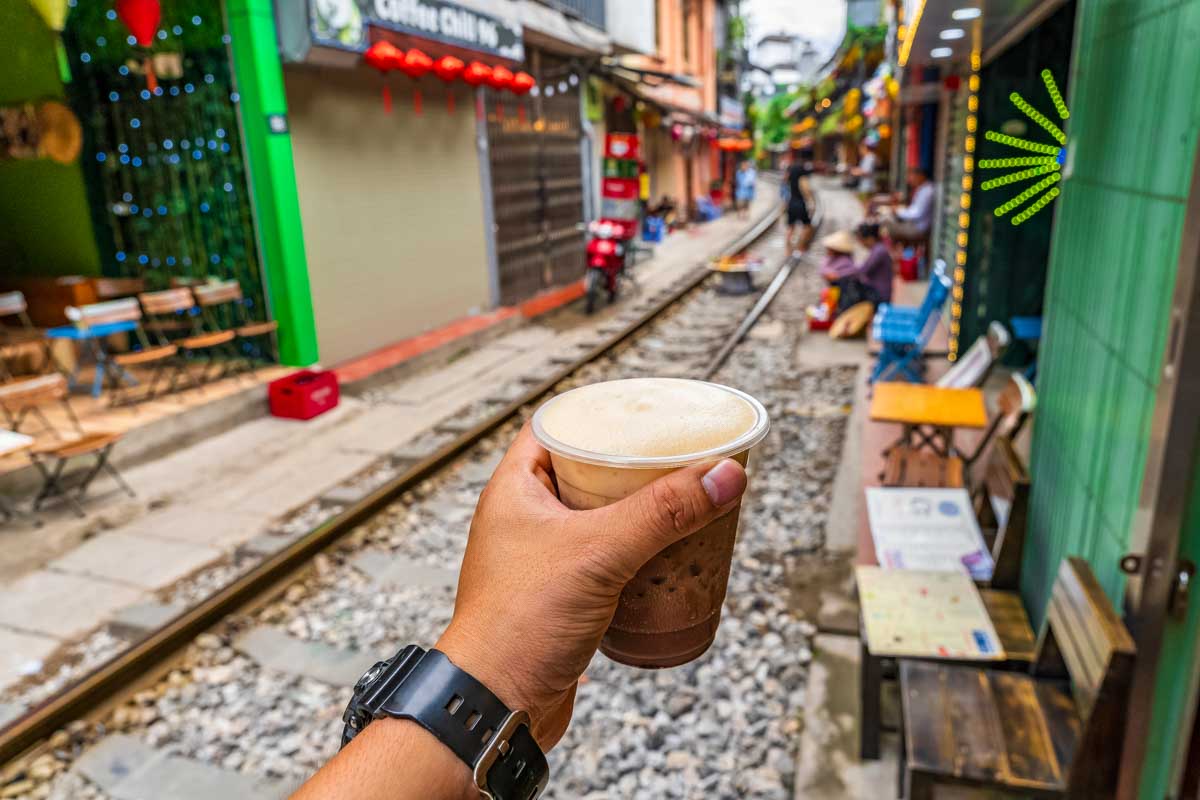 A person holds a drink on Train Street Vietnam Hanoi