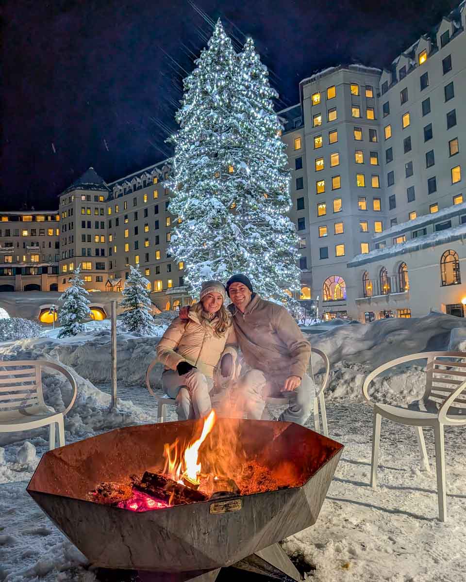 Bailey and Daniel sit at a fire outside at night in the winter at Fairmont Chateau Lake Louise in Lake Louise Alberta Canada (1)