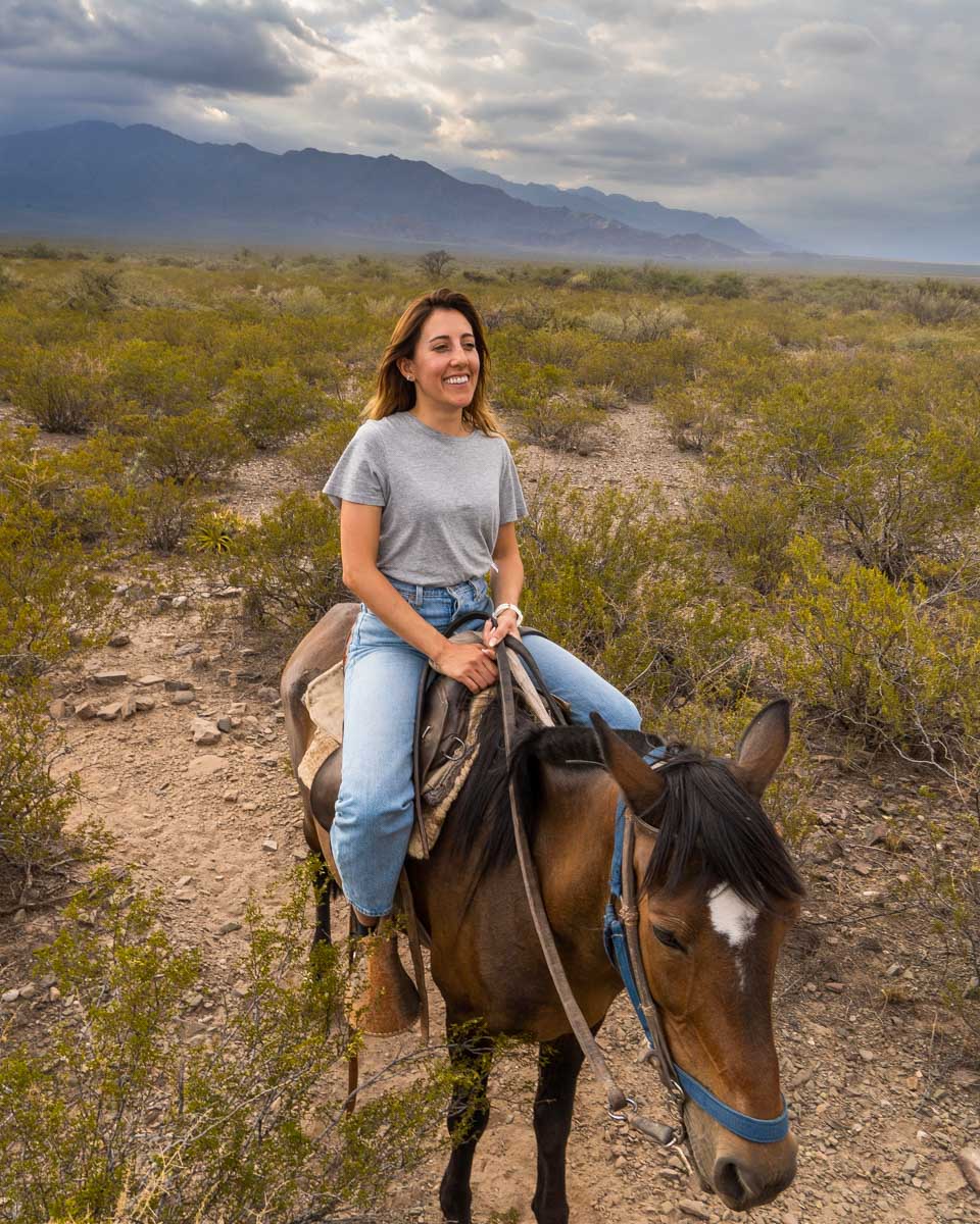 A woman rides a horse in the mountains outside of Mendoza Argentina